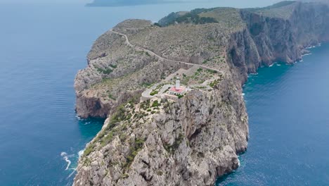 Vista-Aérea-Lejana-De-La-Torre-Del-Faro-En-El-Escarpado-Cabo-De-Piedra-Caliza,-Mallorca