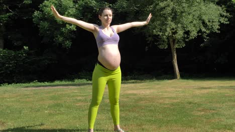 Pregnant-caucasian-woman-slowly-raising-and-lowering-arms-in-the-garden