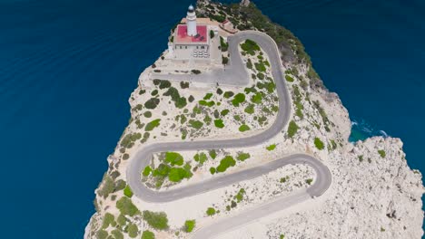 Stunning-aerial-view-of-lighthouse-on-cliff-near-turquoise-water,-Mallorca