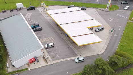 Cars-pulling-into-Shell-petrol-gas-station-in-Devon-UK,-June-2024,-showing-forecourt,-building,-and-parking