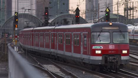 Yellow-Frankfurt-bound-train-departing-from-station-at-dusk,-sharp-focus-on-train-with-blurred-background