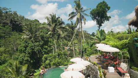 Tourists-Relaxing-in-Swimming-Pool-With-Tropical-Jungle-Around-in-Tis-Cafe,-Ubud-on-Sunny-Day