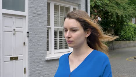 Happy-young-caucasian-woman-walking-down-street-in-london-and-laughing