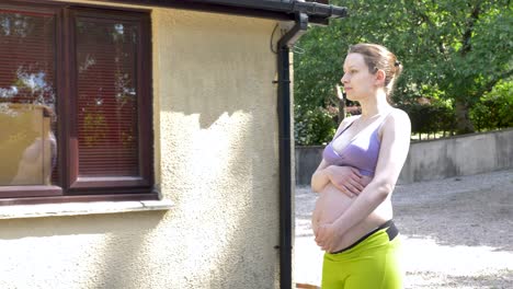 Pregnant-woman-holding-belly-while-walking-up-to-house