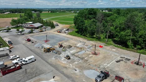 Aerial-approaching-shot-of-working-excavator-on-construction-site-of-housing-area-in-american-suburb