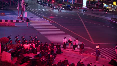 Pedestrians-wait-on-crosswalk-at-intersection-city,-night-time,-Thamrin-Road-Jakarta