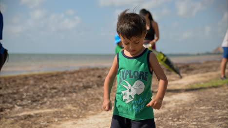 Zeitlupe-Eines-Jungen-Mexikanischen-Lateinamerikanischen-Jungen,-Der-Mit-Einer-Gruppe-Von-Menschen,-Die-Sich-Freiwillig-Melden,-Um-Den-Strand-In-Cancun,-Mexiko,-Aufzuräumen,-Am-Strand-Spazieren-Geht