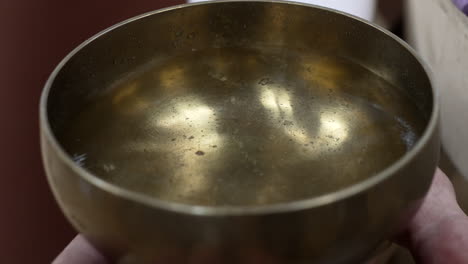 A-Hand-Rubbing-a-Partially-Filled-Singing-Bowl-With-a-Wand-for-a-Sound-Bath-Session-in-the-Sacred-Valley-of-the-Cuzco-Region,-Peru---Close-Up