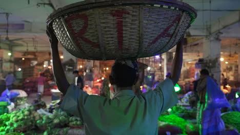 Bengali-man-gracefully-walks-through-Karwan-Bazar-market-indoors,-holding-a-traditional-woven-basket