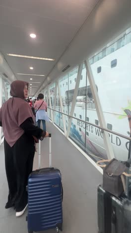 Rear-View-Of-Passengers-Walking-On-Connecting-Bridge-To-Cruise-Ship