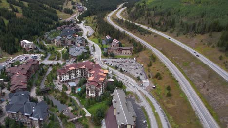 Drone-Shot-of-Copper-Mountain-Ski-Resort-Buildings-and-Traffic-on-I-70-Interstate-Highway-in-Summer-Season,-Colorado-USA