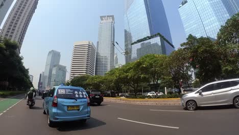 Drive-situation-between-cars-and-building-on-busy-metropolitan-road,-Jakarta