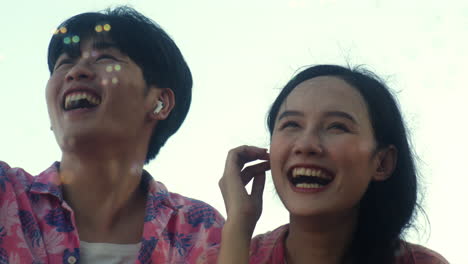 Young-asiatic-couple-in-love-dancing-together-outdoor-while-making-soap-bubble-during-hot-summer-day