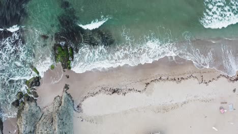 Still-top-down-view-of-waves-hitting-the-beach