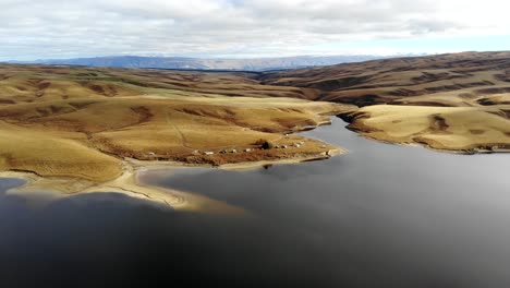 Rising-shot-of-fishing-huts-on-Lake-Onslow-revealing-dramatic-landscape-in-Central-Otago