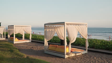 Gazebo-De-Lujo-Con-Tumbonas-En-El-Patio-Al-Aire-Libre,-Tumbona-Con-Cortina,-Cojines,-Almohadas-Y-Dosel-En-Un-Salón-Al-Aire-Libre-Frente-A-La-Playa-Con-Vistas-Al-Mar-Al-Atardecer-En-Seminyak,-Bali,-Indonesia