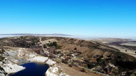 Aerial-View-of-Remote-Gold-Rush-Town-St-Bathans-with-views-of-Central-Otago-appearing-in-background