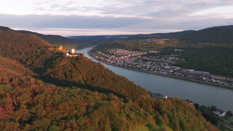 Drone-flies-past-hillside-castle-with-Rhine-river-and-small-village-in-the-background