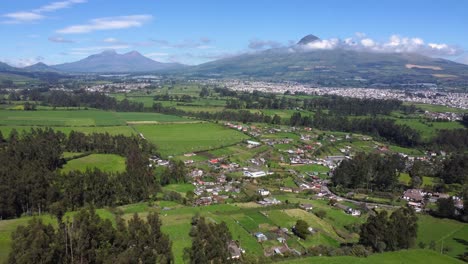 Greenland-and-towns-of-the-province-of-Pichincha,-Ecuador,-Machachi,-the-illinizas-and-volcano-in-the-background,-dolly-shot-with-copy-space