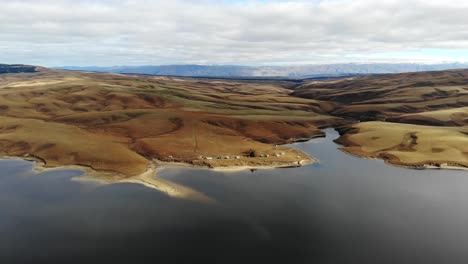 Small-fishing-huts-sitting-in-dramatic-landscape-of-high-plateau-next-to-Lake-Onslow-in-Central-Otago