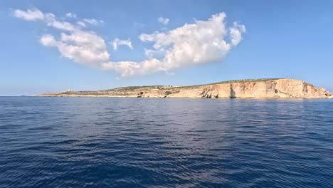 A-distant-view-from-a-boat-approaching-Comino-island-in-the-Mediterranean-Sea,-Malta