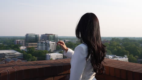 Young-businesswoman-contemplating-on-a-rooftop-balcony-looking-over-the-city,-success,-drive,-corporate,-financial