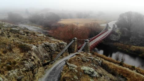 Car-driving-across-historic-bridge-in-Ophir,-Central-Otago,-New-Zealand,-with-tranquil-mist-in-background