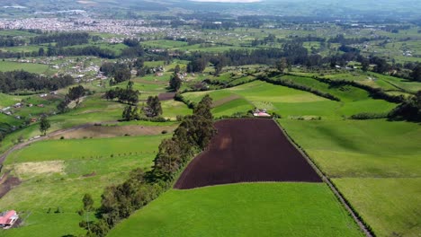 Aerial-drone-flight,-green-fields-of-Province-of-Pichincha,-Ecuador,-city-of-Machachi-in-the-background,-dolly-shot