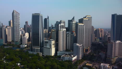 Drohne-Nähert-Sich-Einem-Hochhaus-In-Der-Sonnenbeschienenen-Skyline-Von-Makati,-Manila,-Philippinen