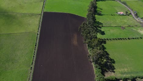 Vuelo-De-Drones-Sobre-Un-Campo-Marrón-Y-El-Barrio-Guitig-En-El-Cantón-Mejía,-Ecuador-En-Un-Día-Soleado,-Tiro-Con-Plataforma-Rodante