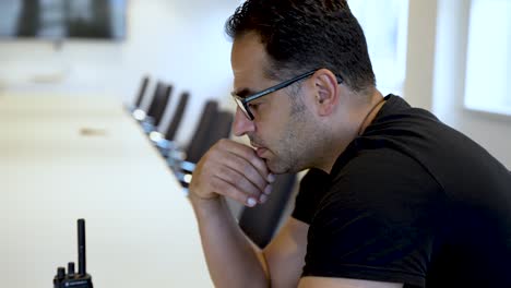 A-pensive,-athletic-European-male-in-an-empty-meeting-room-wearing-glasses-and-thinking-deeply