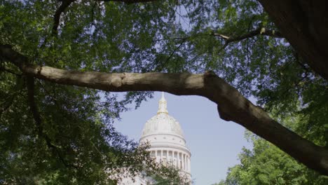 West-Virginia-state-capitol-building-in-Charleston,-West-Virginia-with-gimbal-video-pulling-back-through-trees