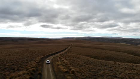 Car-driving-down-remote-and-lonely-road-in-dramtic-landscape-of-Central-Otago-steppe