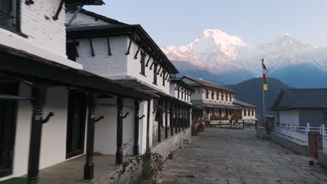 Aerial-drone-shot-of-a-traditional-Nepali-home-in-Ghandruk-Village,-Kaski,-Nepal,-with-the-Annapurna-and-Machhapuchhre-mountain-ranges-in-the-background