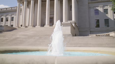 Water-fountain-in-front-of-the-West-Virginia-state-capitol-building-in-Charleston,-West-Virginia-with-video-tilting-up-in-slow-motion