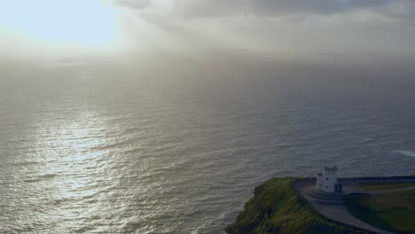 Static-shot-featuring-O'Brien's-Tower-with-stunning-sunlight-reflection-on-the-ocean-at-the-Cliffs-of-Moher