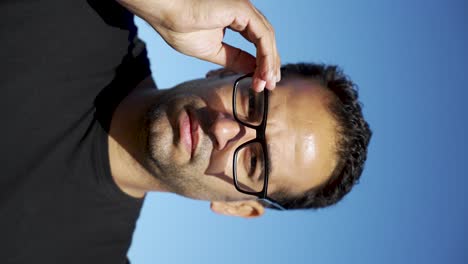 European-athletic-male-putting-on-glasses-on-a-sunny-rooftop,-looking-confident-and-thoughtful