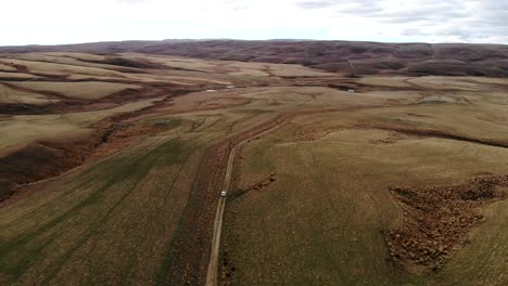 Weißes-Auto-Fährt-Abgelegene-Straße-Mitten-Im-Nirgendwo-In-Central-Otago-Entlang