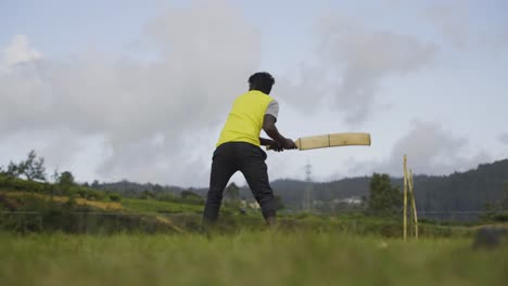 Mann-Im-Gelben-Hemd-Spielt-Cricket-Auf-Einem-Grünen-Feld-In-Sri-Lanka-Unter-Einem-Bewölkten-Himmel