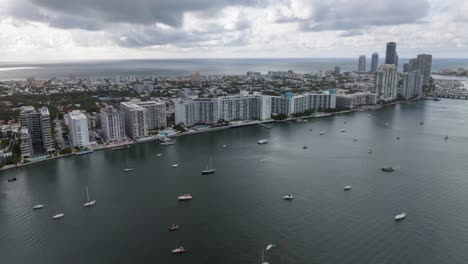 Aerial-time-lapse-of-Miami-coastline-with-high-rises,-Biscayne-Bay,-and-drifting-boats