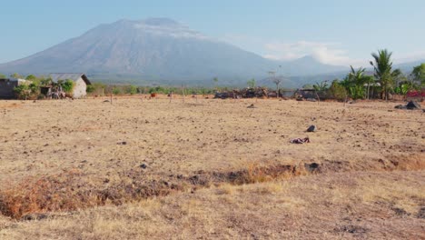 A-view-of-a-small-hut-nestled-amongst-the-dry-landscape-with-a-towering-mountain-in-the-background