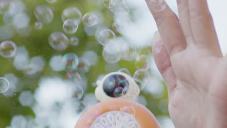 close-up-of-bubble-soap-maker-toy-gun-with-female-hands-playing-during-summer-holiday