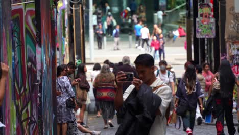 Visitors-walking-through-famous-Hosier-Lane,-a-popular-cobblestone-laneway-with-a-vibrant-array-of-art-murals-and-graffiti-on-the-walls,-a-creative-cultural-street-scene-in-Melbourne-city