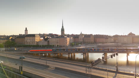 Traffic-on-Central-Bridge-between-Gamla-Stan-and-Södermalm-at-sunrise,-aerial