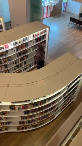 Draufsicht-Einer-Muslimischen-Frau-Mit-Hijab,-Die-In-Der-Modernen-Bibliothek-Spazieren-Geht