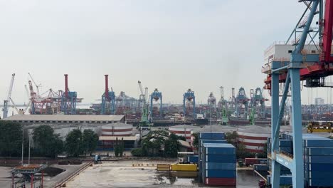 Kamerafahrt-Von-Turmdrehkränen-Und-Stapelcontainern-Im-Industriegebiet-Im-Hafen-Von-Tanjung-Priok