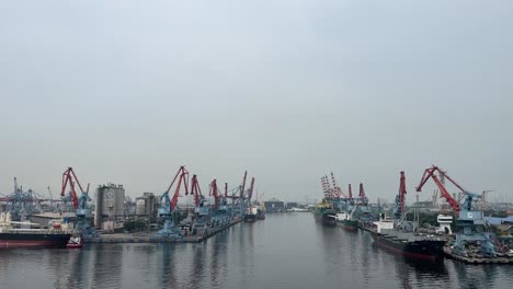 Tanjung-Priok-Geschäftiger-Hafen-Mit-Turmdrehkränen-Und-Strukturen-Aus-Der-Ferne-Unter-Dem-Wolkigen-Himmel