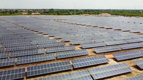 Aerial-drone-flying-low-over-slightly-dusty-solar-panels-park-in-Gambia,-West-Africa-sunny-day