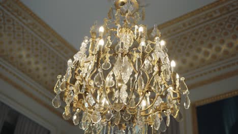 Close-up-pan-left-luxurious-chandelier-interior-expensive-hotel-with-golden-wall