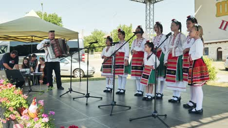 Junge-Mädchen-Des-Bulgarischen-Volkschors-Singen-Beim-Outdoor-Festival-Mit-Akkordeonmusiker